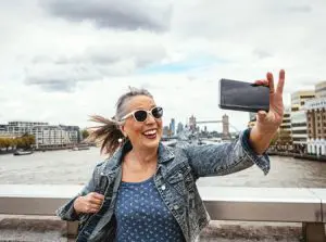 woman smiling and taking a photo of herself near a harbor