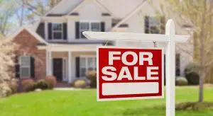 Red for sale sign outside a two story home