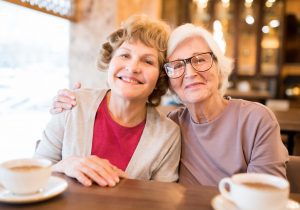 Cheerful senior lady friends in coffee shop