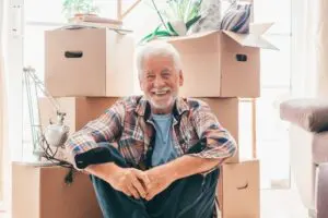 smiling senior man sitting in front of packed moving boxes